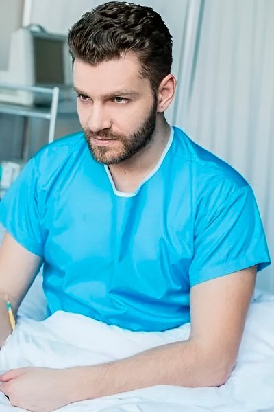 пациент сидит на кровати в палате