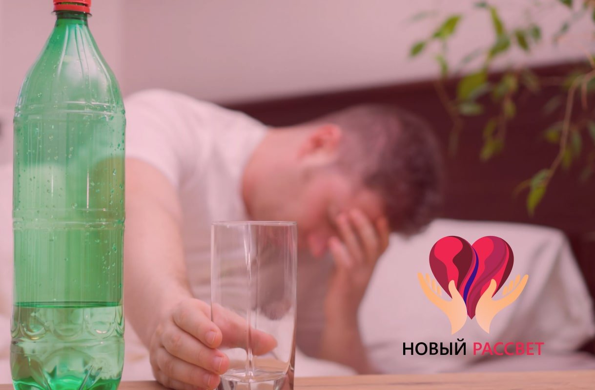 Мужчина сидит на диване и держится за стакан