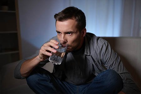 Мужчина пьет воду из стакана